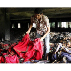 Un trabajador examina restos de chaquetas tras el incendio en la fábrica Tung Hai Sweater, este jueves en Dacca (Bangladés).