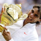 El tenista español Rafael Nadal sostiene sonriente su trofeo tras su victoria sobre el checo Berdych
