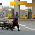 Una mujer ucraniana transporta leña por delante de una estación de servicio cerrada de Mirgorod