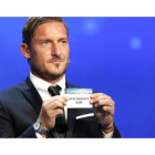 El exfutolista de la Roma Francesco Totti muestra la papeleta del Real Madrid durante el sorteo de la Liga de Campeones. SEBASTIEN NOGIER