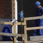 Dos trabajadores colocán elementos de seguridad en un edificio en construcción.