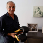 Isidro Tejada, el padre de Saúl, con los guantes de su hijo ante fotos del púgil leonés en su domicilio de Cembranos. MARCIANO PÉREZ