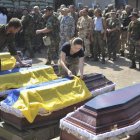 Varios soldados ucranianos cubren con una bandera los ataúdes de los compañeros muertos.