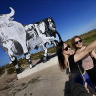 Turistas se acercan a fotografiarse y observar el toro de Osborne que ha aparecido pintado con el escenas del Guernica de Picasso en Santa Pola, Alicante.