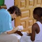 Un voluntario de una organización no gubernamental cura la pierna de una niña guineana herida