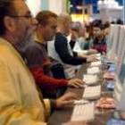 Algunos de los visitantes de la feria en Madrid, se entretienen jugando con ordenadores
