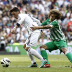 Özil, a la izquierda, se lleva el balón a pesar del agarrón del bético Cañas.