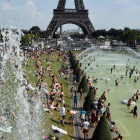 Franceses y turistas, bañándose en las fuentes junto a la torre Eiffel para combatir la canícula, este jueves.