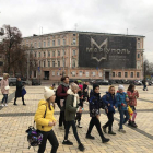 Un grupo de estudiantes se dirigen a la exposición ante un cartel recordando la hazaña de Mariupol. GERVASIO SÁNCHEZ