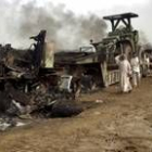 Un grupo de iraquíes pasa ante los restos de un convoy americano atacado en Faluya