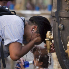 Un turista se refresca en la fuente de Canaletes durante una ola de calor.