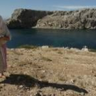 Una anciana pasea por tierras marroquíes con la isla de Perejil al fondo