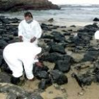 Varios empleados de la empresa estatal Tragsa recogen fuel de la playa cantábrica de Ubiarco