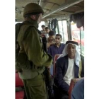 Un soldado registra a varios palestinos en un autobús, en Hebrón