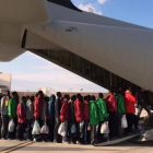 Inmigrantes subsaharianos hacen cola antes de subir a un avión militar que les trasladará a la península italiana, este lunes, en Lampedusa.