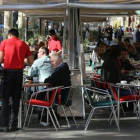 Varios camareros sirven a clientes en terrazas de bares.