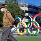 Un hombre protegido por una máscara para evitar posibles contagios da la espalda a los anillos olímpicos instalados en Tokio.  DEMÓFILO PELÁEZ