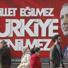 Varias personas pasan por delante de un cartel electoral de Erdogan, este jueves en Estambul.