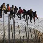 Policías españoles tratan de disuadir a inmigrantes encaramados a la valla de Melilla, fronteriza con Marruecos. /