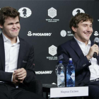El noruego Carlsen (izquierda) sonríe mientras el derrotado ajedrecista ruso Karjakin habla en la rueda de prensa posterior a la partida definitiva.