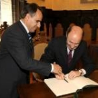Rubalcaba firma en el libro de honor del ayuntamiento ante la mirada de Perandones