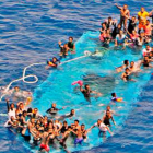 Momento del rescate de los migrantes que esperan sobre el casco de la embarcación.