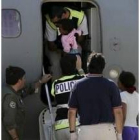 Un policía español ayuda a subir al avión a la única niña del grupo