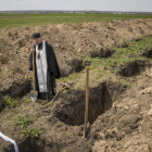 Un religioso observa las fosas en el cementerio militar de Dnipro. MIGUEL GUTIÉRREZ