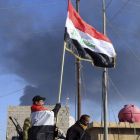 Un soldado del Ejército iraquí alza la bandera nacional dentro del complejo gubernamental.