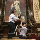 Operarios del Ayuntamiento de Barcelona retiran el busto del rey Juan Carlos del salón de plenos municipal antes de guardarlo en una caja de cartón.