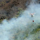 Un helicóptero, en medio del humo, sobrevuela el robledal en la zona de San Clemente.