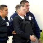 Ricardo Miguel Cavallo, esposado, custodiado por dos policías mexicanos antes de viajar a España