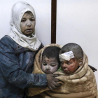 Una mujer abraza a sus hijos tras resultar todos heridos en un bombardeo en el barrio de Al Barze.