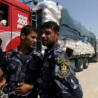 Miembros de las fuerzas de seguridad de Hamas inspeccionan camiones cargados de comida que llegan de