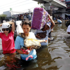 Tailandeses cruzan con pertenencias una calle de Bangkok.
