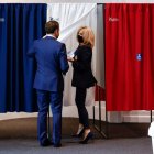 Macron y su esposa Brigitte en una cabina electoral para votar ayer en París. CHRISTIAN HARTMANN