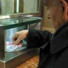 Un hombre retira dinero de una ventanilla de una entidad bancaria