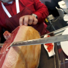 Un hombre corta jamón.