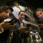 Un grupo de turistas argentinos consultan sus móviles, en Barcelona.