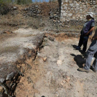 Los arqueólogos miran uno de los muros del poblado.