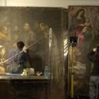 Dos personas trabajan en la restauración de uno de los lienzos