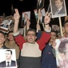 Unos manifestantes corean eslóganes a favor de Siria mientras portan retratos del presidente