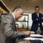 El alcalde Agustín Navarro firma documentos observado por el tránsfuga José Bañuls.
