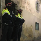 Dos mossos ante el portal de la calle de la Riera Alta donde se ha cometido el crimen.