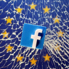 Ilustración de un logo de Facebook sobre un cristal roto con una bandera de la UE detrás.