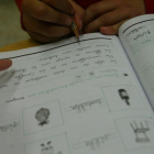 Una niña escribe en un cuaderno de trabajo. DL