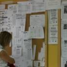 Una mujer observa un panel donde cuelgan ofertas de empleo