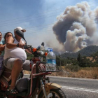 Una familia turca escapa con su motocicleta de la zona rural de Marmaris azotada por varios fuegos. ERDEM SAHIN