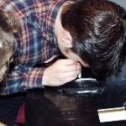 Dos jóvenes consumen cocaína, esnifándola por la nariz a través de un canutillo de papel