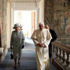 La reina Isabel II y el príncipe Felipe caminan junto al papa Benedicto XVI por los pasillos del pal